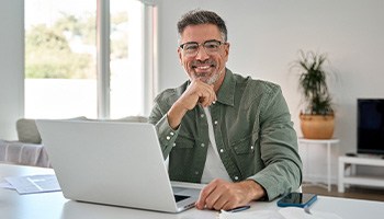 Man smiling while working on computer at home