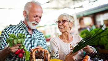 Senior couple smiling while shopping for vegetables