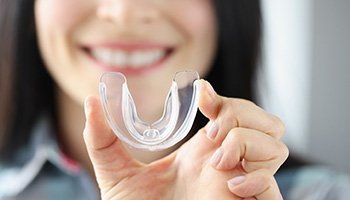 Dental implants patient in South Portland holding a mouthguard